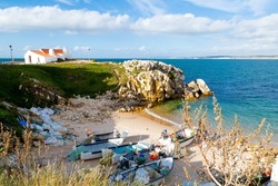Beautiful fishermen creek with the fishing boats on the sand and Saint Stephen hermitage in Peniche