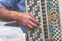 Hand detail of elderly person playing chromatic accordion at a folk festival