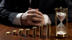 Piles of coins growth, sand flowing in hourglass, businessman waiting for profit