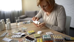 Old female taking capsules from bottle self-medication pills addiction obsession