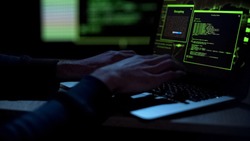 Cybercriminal creating malicious software, typing on laptop keypad, closeup