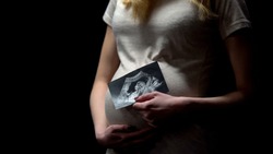Young pregnant lady holding childs x-ray, happy motherhood, baby expectation