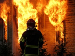 Firefighter watches old, abandoned house burning down.