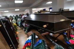Inside the funeral service store are wooden coffins and wreaths with sparkling flowers