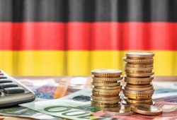 Euro banknotes and coins in front of the national flag of Germany