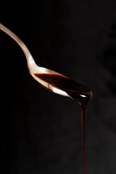 Dripping caramel from a spoon on a dark background. Liquid sweetness.