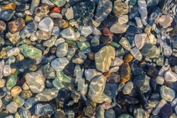 Sea stones in the sea water. Pebbles under water. The view from the top. Nautical background. Clean sea water. Transparent sea.
