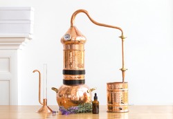 Distilling apparatus alembic with esential oil flowers at the wooden table.