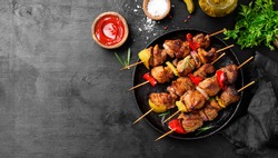 Kebabs - grilled meat skewers, shish kebab with vegetables on black wooden background.	
