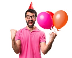 Lucky handsome young man holding balloons over isolated white background