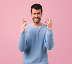 Handsome man annoyed angry in furious gesture on pink background
