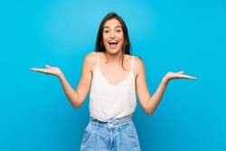 Young woman over isolated blue background with shocked facial expression