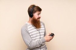 Redhead man with long beard over isolated background playing at videogames