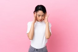 Young Vietnamese woman isolated on pink background with headache