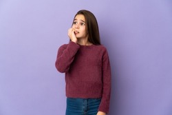 Little girl isolated on purple background is a little bit nervous