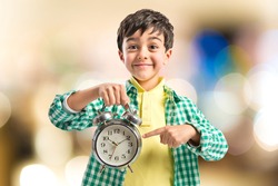 Boy holding an antique clock over white background 