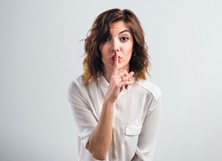 Pretty girl making silence gesture over grey background