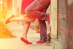 Young couple kissing outdoor. Male and female legs. Cross processed image for vintage look