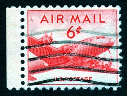 Vintage cancelled USA airmail postage stamp showing an red image of a cargo aeroplane