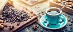 A turquoise cup of aromatic black coffee and coffee beans on the table. Morning Coffee Espresso for breakfast in a beautiful turquoise cup.