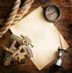 Old compass, astrolabe and rope on vintage paper. Adventure stories background.