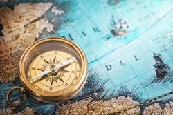Old compass on vintage map. Adventure stories background. Retro style