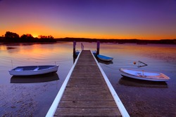 Little boats moored to a jetty at sunset.This is a quiet cove on the Brisbane Waters, Central Coast Australia