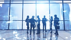 Silhouettes of business people in panoramic office with double exposure of blurry cityscape. Concept of business meeting and teamwork. Toned image