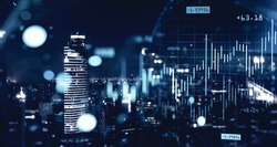 Double exposure of blurry financial graphs over night cityscape background. Concept of trading. Toned image