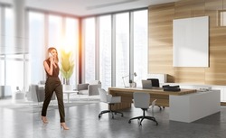 Businesswoman wearing formal dress is walking at office workplace talking on smartphone. Panoramic window with city skyscraper and white empty poster. Concept of successful business people