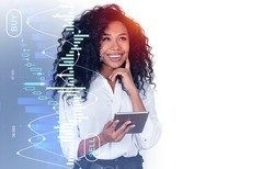Smiling pensive black businesswoman portrait using tablet, forex diagrams hologram with candlesticks, buy and sell. Concept of online trading and consulting. Copy space