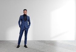 African American businessman wearing formal suit is standing in hands in pocket pose near empty white wall in background. Concept of model, successful business person