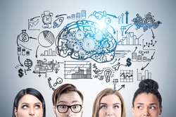 Close up of a group of young business people standing near a gray wall with a brain and gears sketch and a startup sketch drawing on it. Toned image