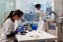 Biotechnology scientist looking through microscope analyzing genetical material. Medicine, biotechnology researcher in advanced pharma lab, examining virus evolution.
