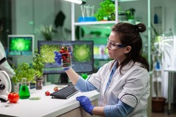 Specialist researcher holding organic strawberry analyzing gmo fruits for microbiology medical experiment. Biologist woman working in medicine agriculture lab discovering genetic mutation on fruit