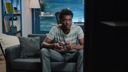 Man playing video games on tv console with controller for entertainment. Young person holding joystick for online play on television at home. Adult gaming and having fun with gadgets.
