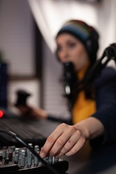 Close up of woman using streaming equipment live with headphones and microphone. Gamer talking to audience on online broadcast, live streaming on computer. Streamer with electronic gadget