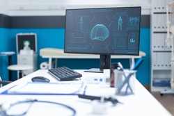 Computer standing on table in empty doctors office having body radiography on screen during medical consultation. Hospital room equipped with professional examination tools. Anatomical skeleton