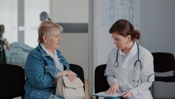 Close up of senior woman and doctor talking about diagnosis in waiting room, giving medical advice and support to sick patient. Pensioner discussing with medic about healthcare in lobby.