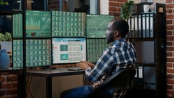 Male broker using forex trade exchange statistics on multiple monitors, working with market charts and real time stocks sales. Hedge fund profit share to buy and sell money. Tripod shot.