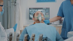 Patient with oxygen mask receiving anesthesic in dentistry cabinet, getting ready for stomatological procedure with dental tools and drill to polish caries. Oral care anesthesia on man.