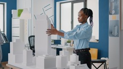 Woman placing blueprints plan on table to design building model and construction layout. Architect using maquette and industrial sketch to create structure for project development.
