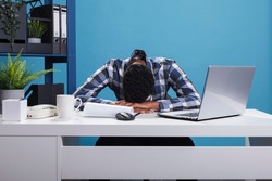 Exhausted and tired young adult office worker falling asleep on desk because of overtime work hours. Burnout fatigued company employee being sleepy and stressed because of huge work effort.