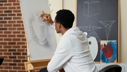 African american student using pencil to draw vase on canvas, learning creative skills at drawing school lesson. Artwork creation using practice tools and instruments for personal development.