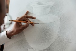 Close up of creative student hand sketching vase model on white canvas learning new sketch skill during art class in educational school studio. Artist man drawing illustration using graphic pencil