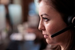 Telemarketing sales worker answering client call on headset, talking to people on remote helpline support. Young telework operator using customer care service equipment. Close up.