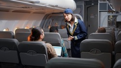 Female stewardess asking passengers about airline services and flying, boarding travellers on airplane seats. Travelling with international airways, chatting on aeroplane jet and going on vacation.