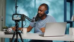 Influencer using podcast equipment and headphones recording on camera. Vlogger filming video with modern equipment and gear for online podcast on social media. Blogger with technology