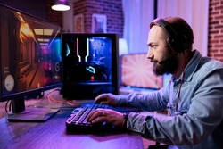 Modern man enjoying action video games championship on computer, playing online tournament with multiple players. Male player attending gaming competition for streaming content.