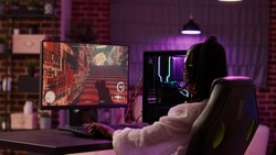 Over shoulder view of african american gamer girl playing online games using gaming pc setup spending relaxing time at home. Woman using modern technology for entertainment and streaming tournament.